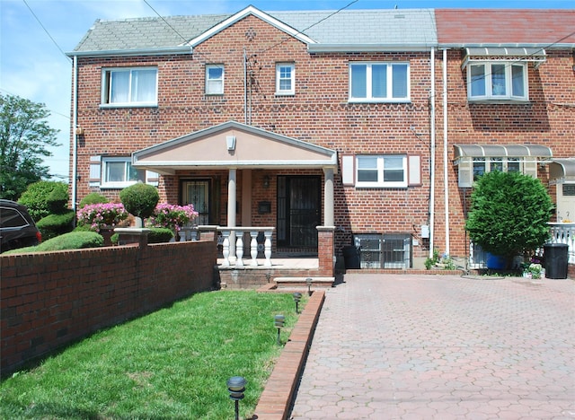 view of front of home with a porch, brick siding, and a front yard