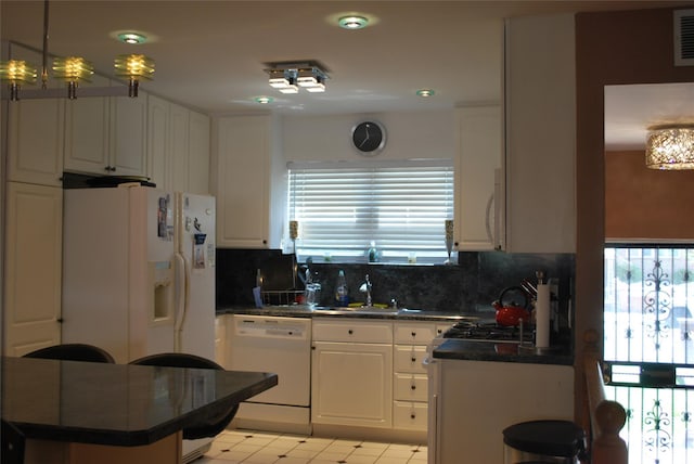 kitchen featuring white appliances, dark countertops, healthy amount of natural light, and backsplash