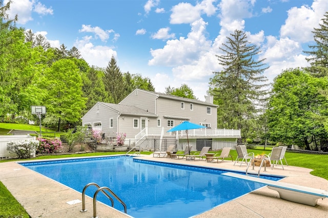 view of swimming pool with a patio, a diving board, view of wooded area, and stairway