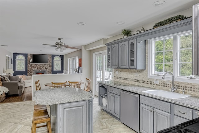 kitchen with dishwasher, a sink, gray cabinetry, plenty of natural light, and recessed lighting