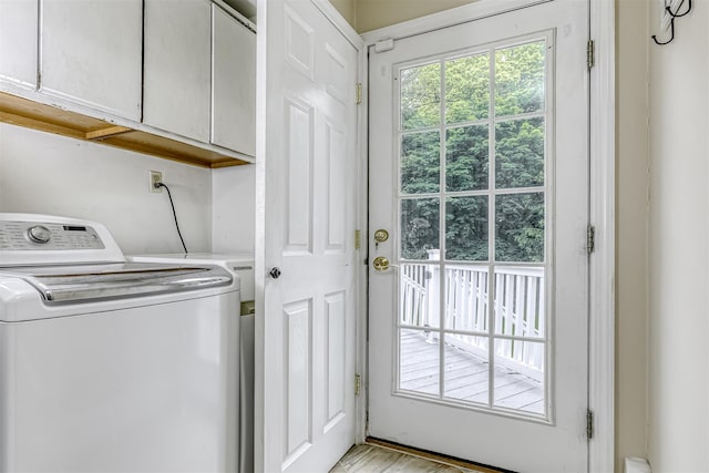 clothes washing area with cabinet space and light wood-style flooring