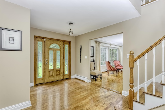 foyer featuring a baseboard radiator, wood finished floors, stairway, and baseboards