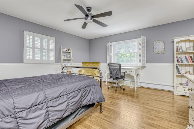 bedroom featuring light wood-style flooring, a baseboard heating unit, a baseboard radiator, and ceiling fan