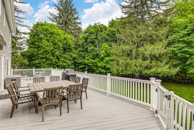wooden terrace with outdoor dining area, a grill, and a lawn