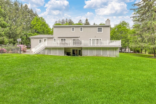 back of house with a wooden deck, a chimney, and a lawn