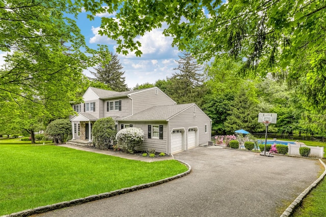 view of front of property with driveway, a front lawn, a garage, an outdoor pool, and roof with shingles