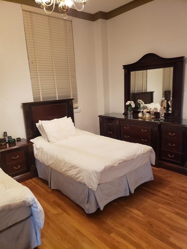 bedroom with a chandelier, wood finished floors, and ornamental molding