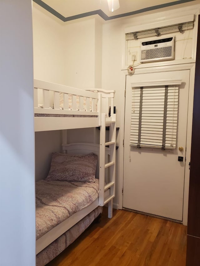 bedroom featuring wood finished floors and a wall mounted air conditioner
