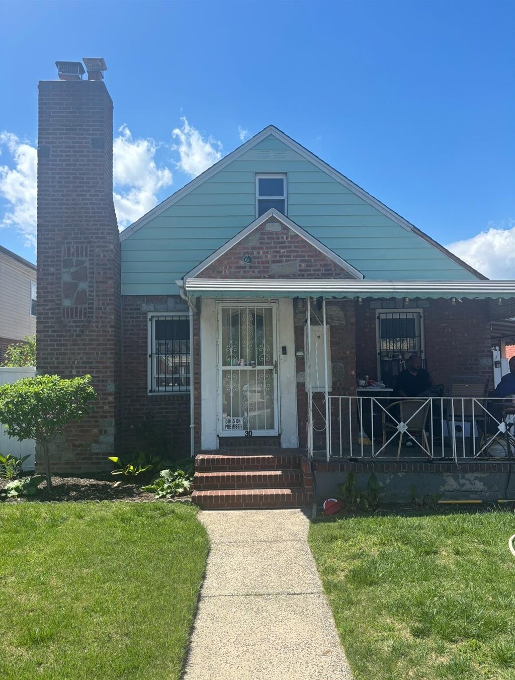 117-30 220th St, Cambria Heights, NY 11411 - bungalow-style home with brick siding, a porch, and a front yard