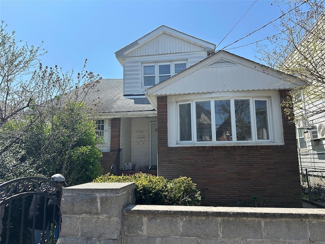 view of front facade with brick siding, fence, and cooling unit