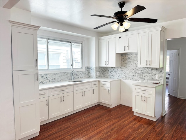 kitchen with a sink, dark wood finished floors, a ceiling fan, decorative backsplash, and white cabinets