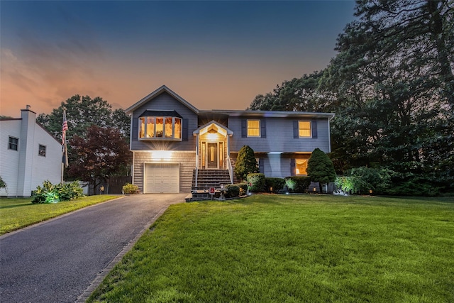 raised ranch with driveway, a front yard, and a garage