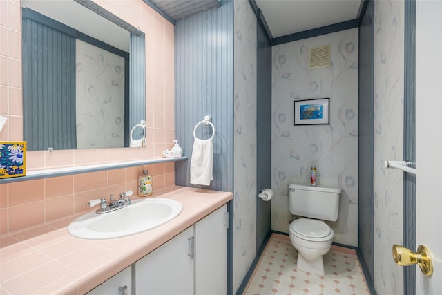 bathroom with toilet, baseboards, vanity, and tasteful backsplash