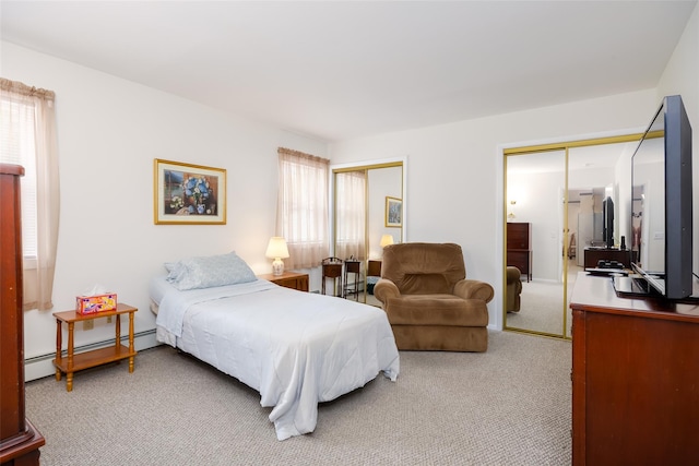 bedroom with a baseboard heating unit, light colored carpet, two closets, and multiple windows