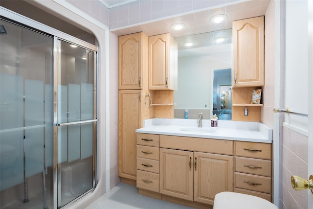 full bathroom with a stall shower, vanity, tile patterned floors, toilet, and tile walls