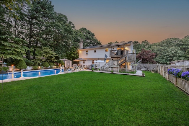 back of property at dusk with a deck, stairway, a shed, an outbuilding, and a chimney