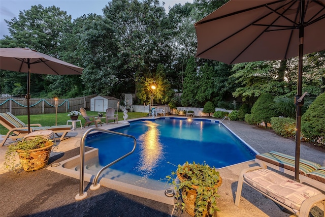 view of swimming pool featuring a storage shed, an outdoor structure, a patio, and view of scattered trees