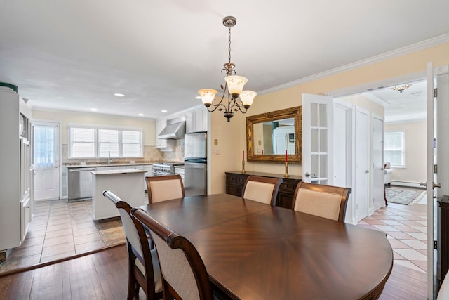 53 Irwin Pl, Huntington, NY 11743 - dining space featuring healthy amount of natural light, baseboard heating, a chandelier, crown molding, and light tile patterned flooring