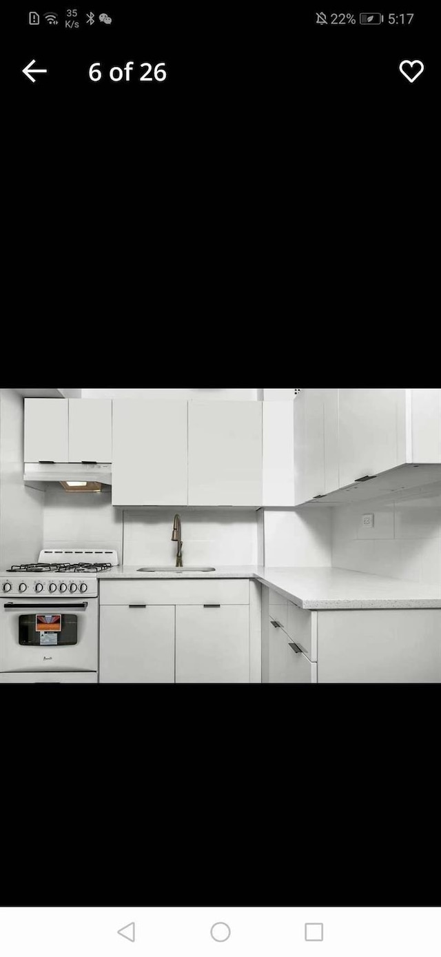 88-30 182nd St Unit 6F, Hollis, NY 11423 - kitchen featuring a sink, white range with gas stovetop, white cabinetry, light countertops, and under cabinet range hood