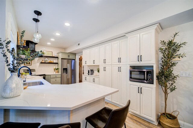 444 Haviland Hollow Rd, Patterson, NY 12563 - kitchen featuring stainless steel appliances, a sink, light wood finished floors, a kitchen bar, and a peninsula