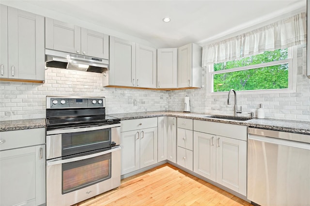 21 James Rd, Monroe, NY 10950 - kitchen featuring appliances with stainless steel finishes, under cabinet range hood, a sink, light wood-style flooring, and light stone countertops