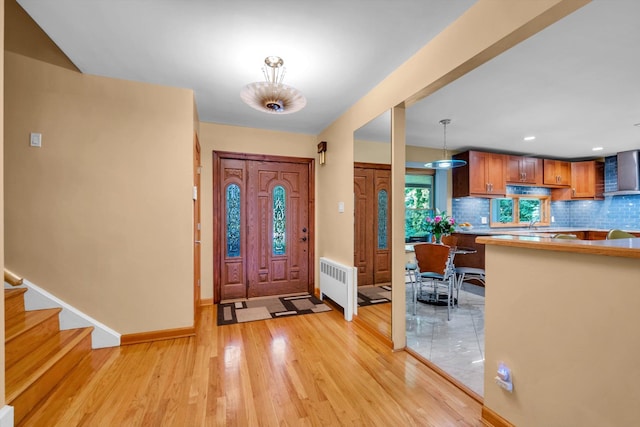 entryway with light wood-style flooring, baseboards, radiator, recessed lighting, and stairs