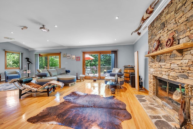 living room with wood finished floors, a fireplace, ornamental molding, and recessed lighting