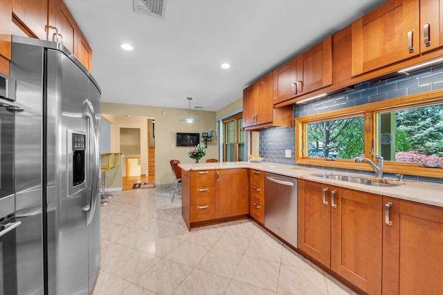 kitchen featuring stainless steel appliances, a sink, brown cabinets, backsplash, and recessed lighting