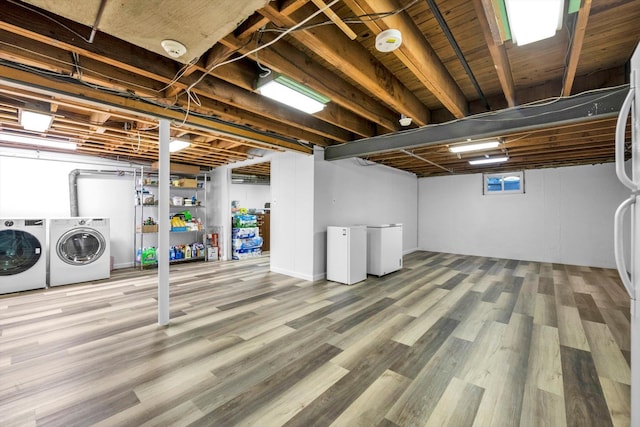 finished basement featuring washer and clothes dryer, refrigerator, freestanding refrigerator, and wood finished floors
