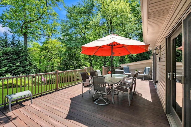 wooden deck featuring outdoor dining space and view of scattered trees