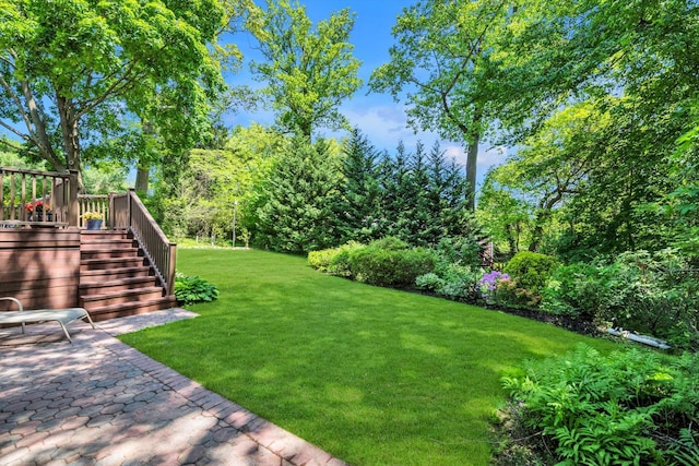 view of grassy yard featuring stairway, a deck, and a patio area