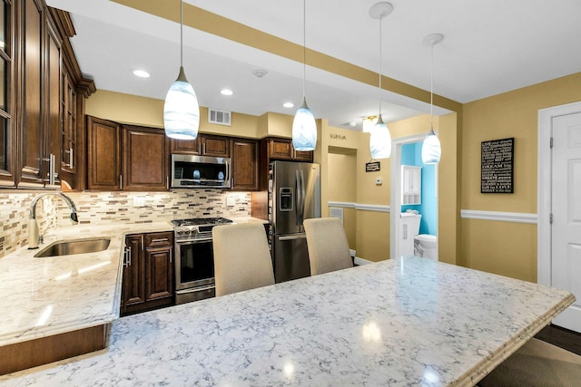 kitchen with appliances with stainless steel finishes, a sink, tasteful backsplash, dark brown cabinets, and recessed lighting