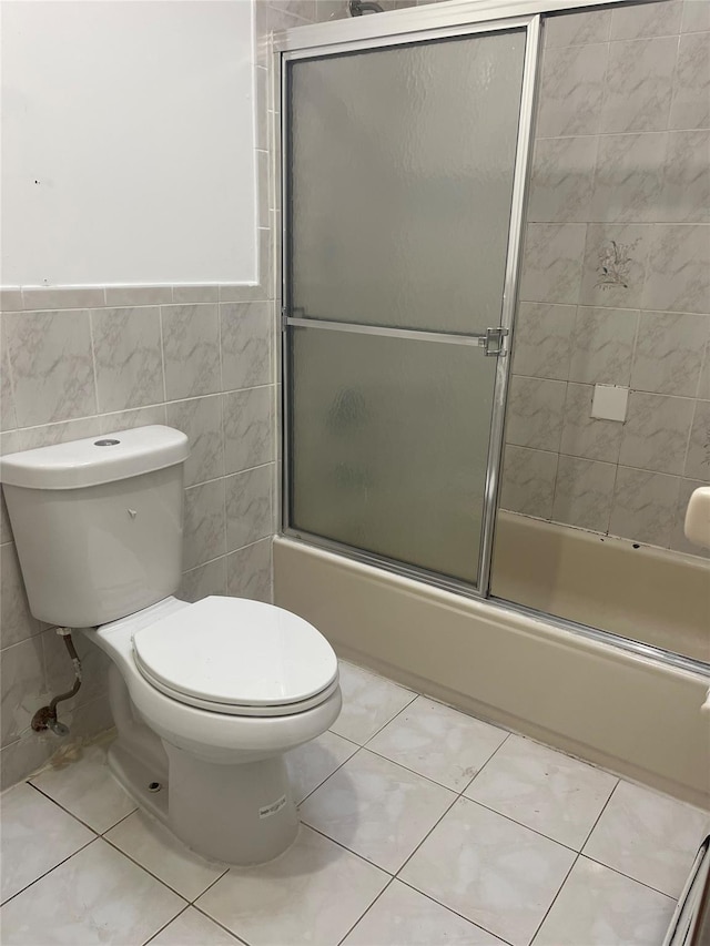 10615 155th St, Jamaica, NY 11433 - full bath with tile patterned floors, tile walls, enclosed tub / shower combo, toilet, and a wainscoted wall