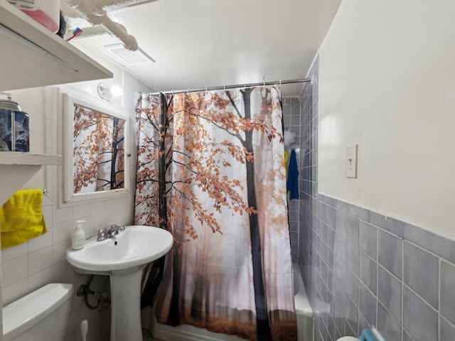 full bath featuring tile walls, toilet, and shower / bath combination with curtain