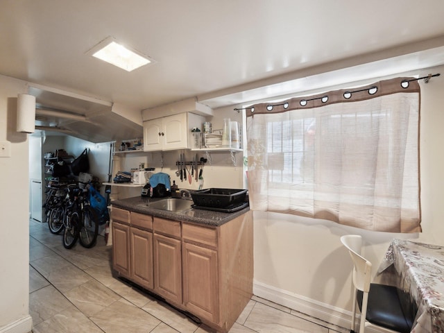 kitchen with a sink, dark countertops, and light tile patterned floors
