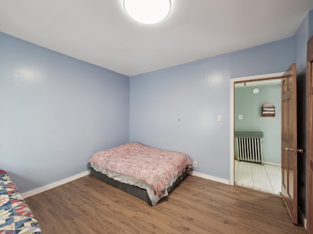 bedroom featuring radiator heating unit, wood finished floors, and baseboards