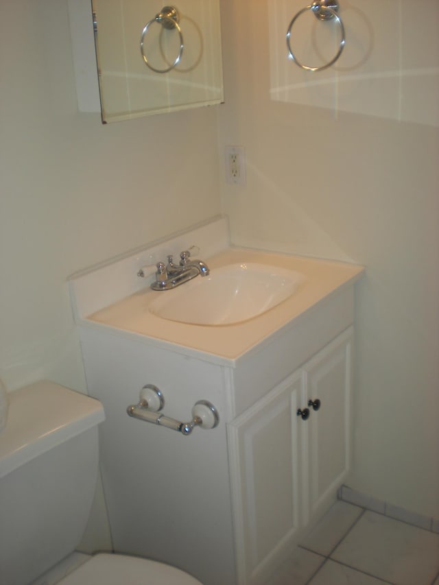 half bath featuring vanity, toilet, and tile patterned floors