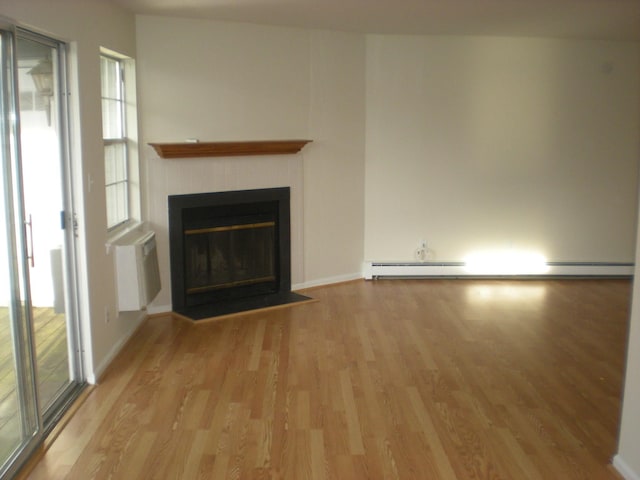 2 Lexington Hl Unit 10, Harriman, NY 10926 - unfurnished living room featuring light wood-style flooring, a fireplace, and a baseboard heating unit