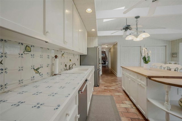 5A/5B Jessup Ln, Quogue, NY 11959 - kitchen featuring a skylight, stainless steel appliances, a sink, white cabinets, and brick floors
