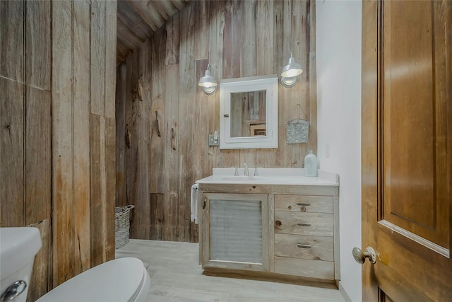 5A/5B Jessup Ln, Quogue, NY 11959 - bathroom featuring toilet, wood walls, and vanity