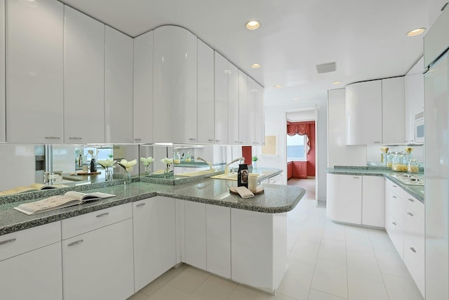 3333 Henry Hudson Pkwy # 23Ef, Bronx, NY 10463 - kitchen with white cabinets, a peninsula, dark stone countertops, white microwave, and recessed lighting
