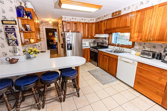 630 New Suffolk Rd, Cutchogue, NY 11935 - kitchen with stainless steel appliances, a sink, under cabinet range hood, light countertops, and wallpapered walls
