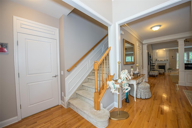 42 Kimberly Dr Unit 42, Westhampton, NY 11977 - stairway featuring crown molding, wood finished floors, decorative columns, a decorative wall, and a fireplace