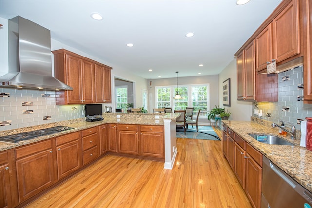42 Kimberly Dr Unit 42, Westhampton, NY 11977 - kitchen with wall chimney exhaust hood, a sink, appliances with stainless steel finishes, light wood-style flooring, and a peninsula