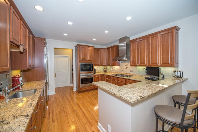 42 Kimberly Dr Unit 42, Westhampton, NY 11977 - kitchen with stainless steel appliances, wall chimney range hood, a sink, a peninsula, and a kitchen breakfast bar