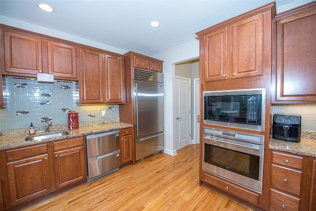 42 Kimberly Dr Unit 42, Westhampton, NY 11977 - kitchen with built in appliances, a sink, light wood finished floors, decorative backsplash, and brown cabinets