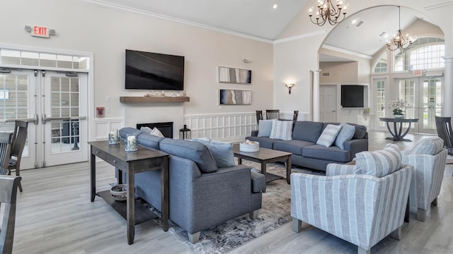 42 Kimberly Dr Unit 42, Westhampton, NY 11977 - living area with a chandelier, french doors, arched walkways, a wainscoted wall, and light wood finished floors