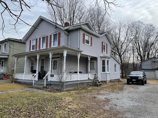 view of front of home featuring a chimney and a porch