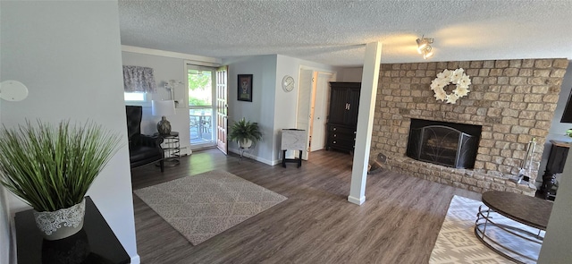 living area with wood finished floors, a textured ceiling, a brick fireplace, and baseboards