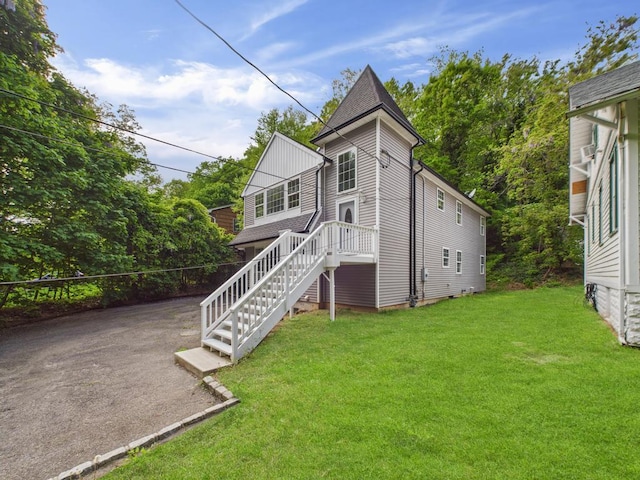 back of property with a lawn and stairway